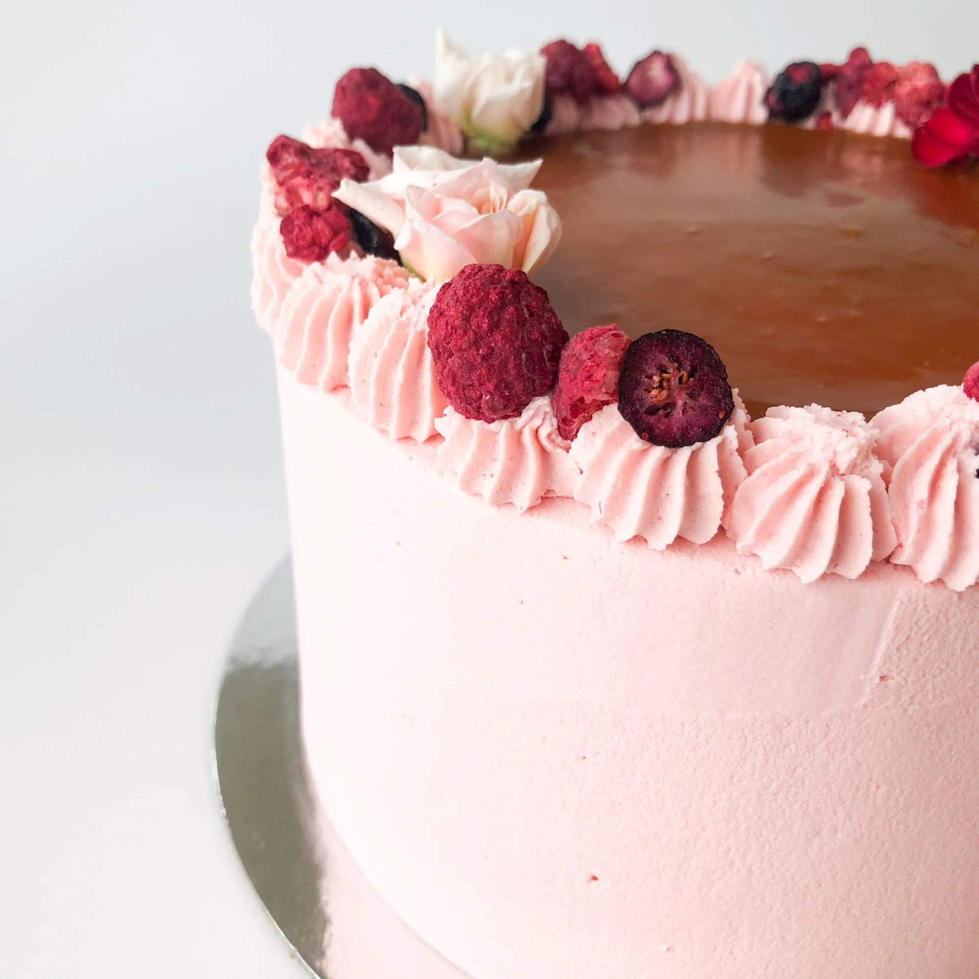 A pink buttercream cake decorated with freeze-dried raspberries